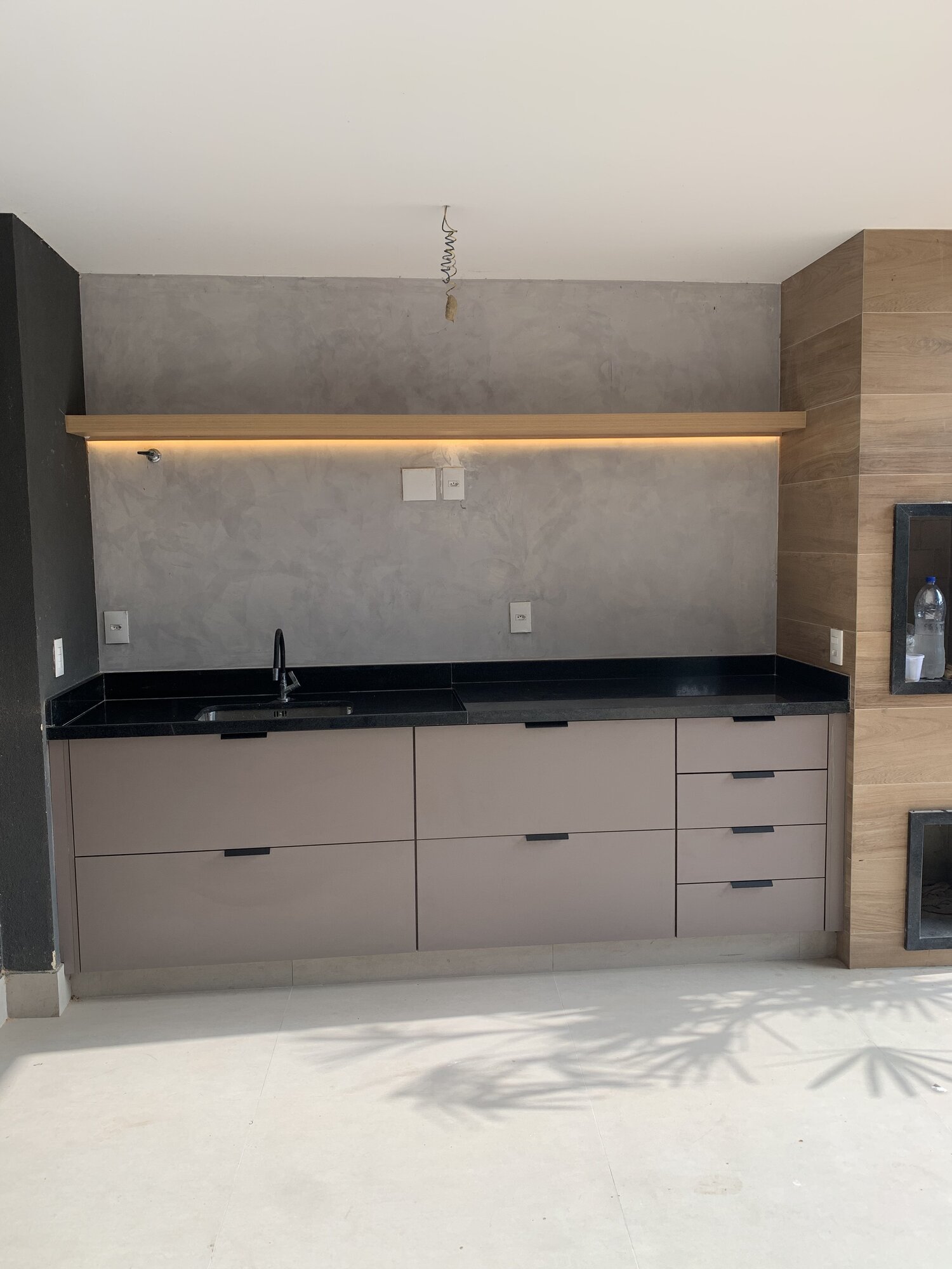 Área gourmet planejada com armários fosco e bancada em granito preto